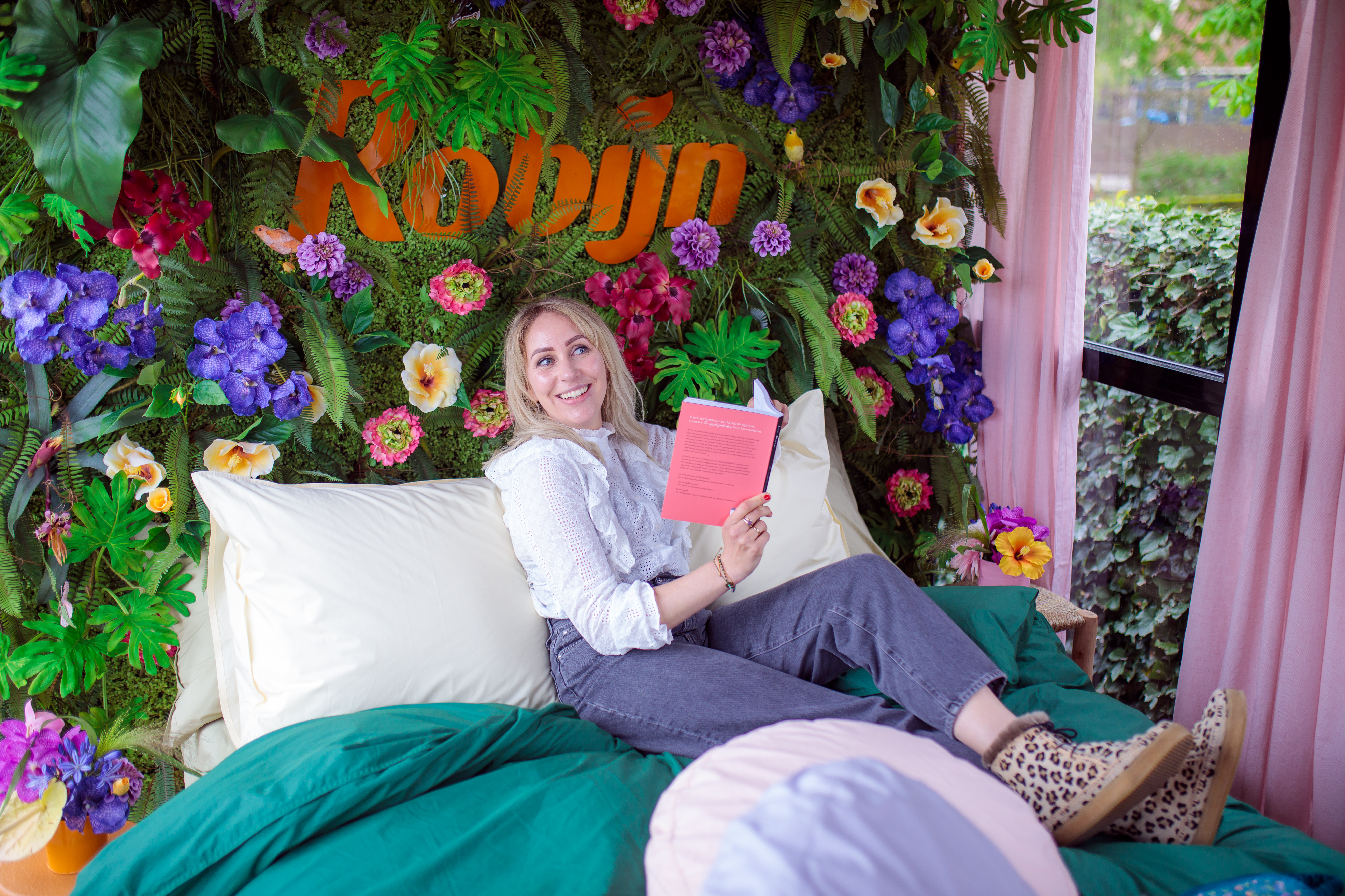Influencer Saskia Weerstand zit op een bed in een fully branded Robijn truck.
